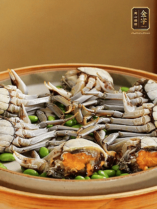 盘底铺毛豆，依次放大闸蟹、咸肉， 淋一圈料酒、豉油。